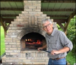 Photo of Steve Bower with wood-fired pizza oven.